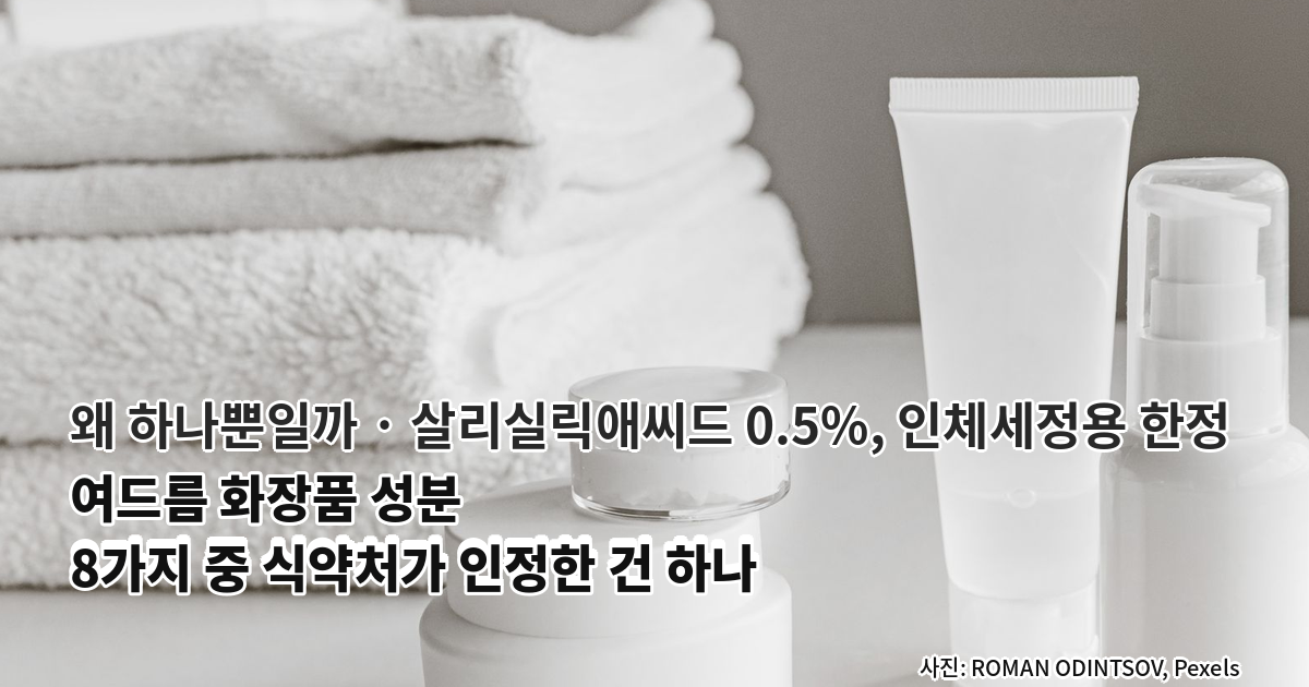 연회색 벽 앞 흰색 테이블 위에 브랜드가 보이지 않는 흰색 크림 단지와 튜브, 펌프 보틀이 모여 있고 왼쪽 뒤로 접어서 쌓아 둔 흰 수건 더미가 흐리게 보인다